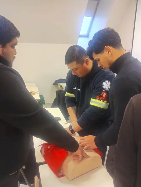 Tres participantes practican compresiones torácicas en un torso de entrenamiento